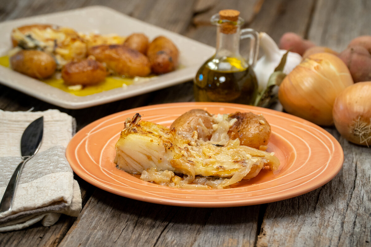 Porção de bacalhau assado com batatas servida com azeite e salsa