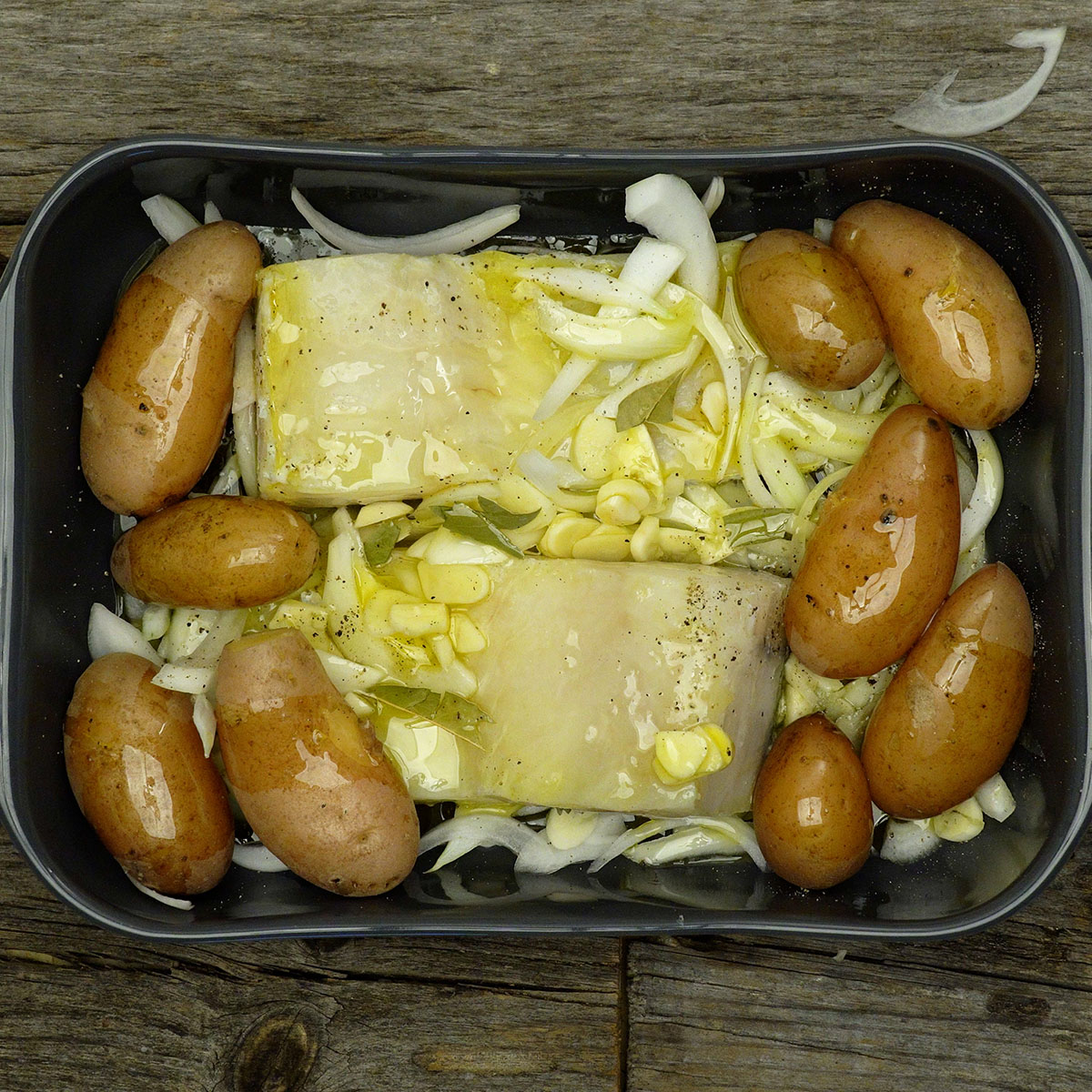 Bacalhau e batatas temperados com azeite, alho e cebola, prontos para ir ao forno