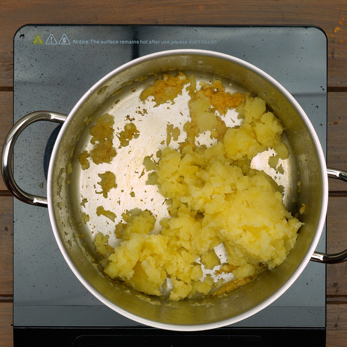 Purê de batata sendo misturado ao refogado de cebola e alho até obter textura homogênea.