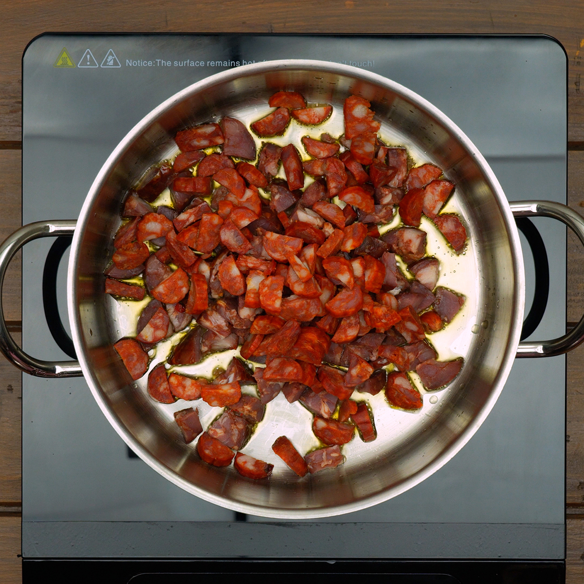 Bacon, chouriço e linguiça sendo refogados em azeite para liberar sabor defumado.