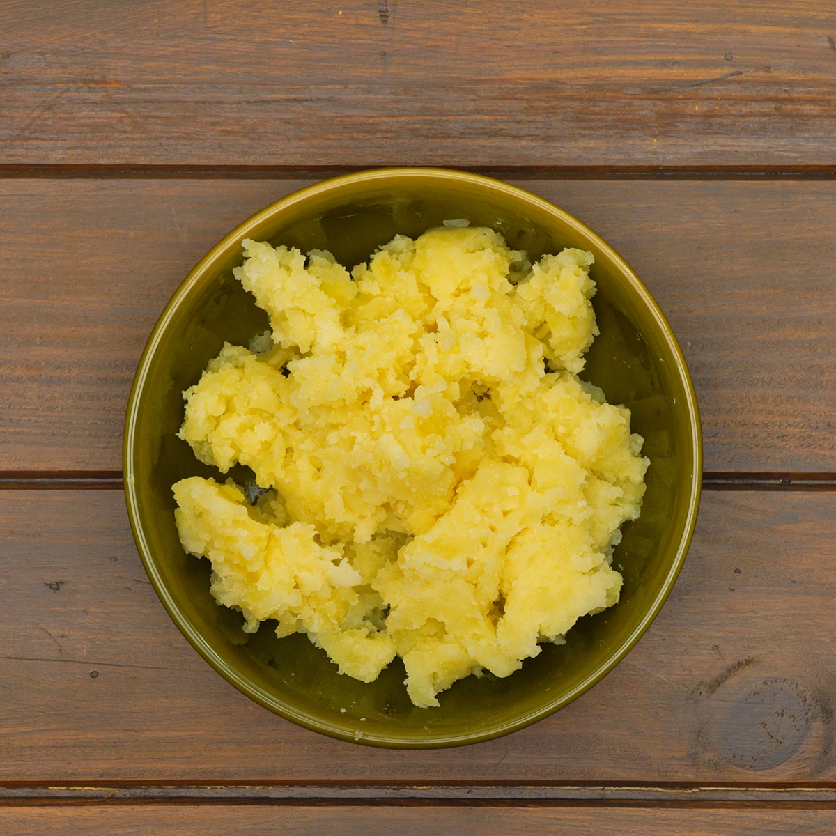Batatas cozidas sendo amassadas até formar purê cremoso para o caldo verde.”