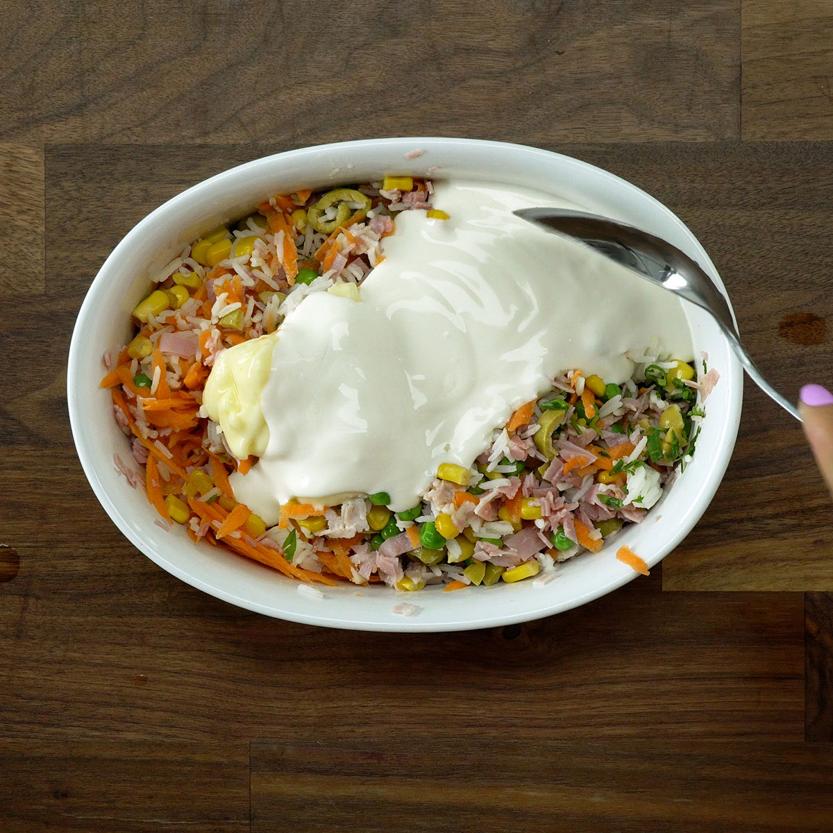 Requeijão cremoso e creme de leite sendo adicionados ao arroz.