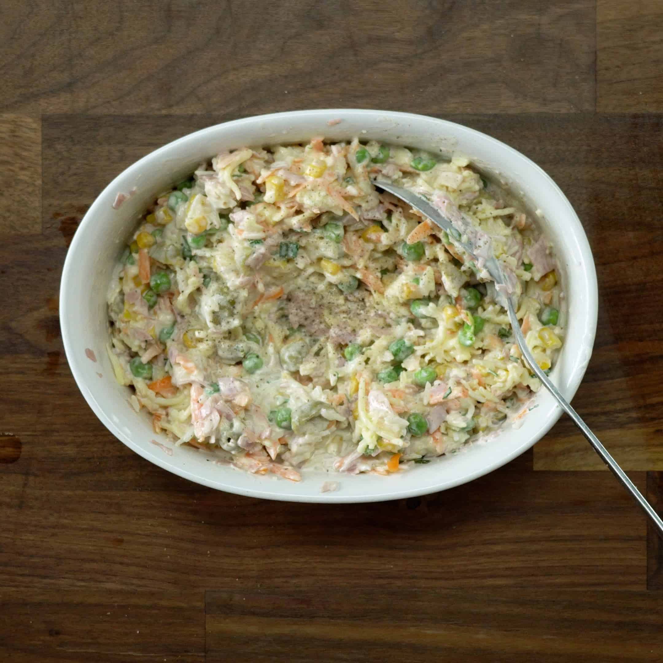 Arroz cremoso sendo temperado com sal e pimenta-do-reino.