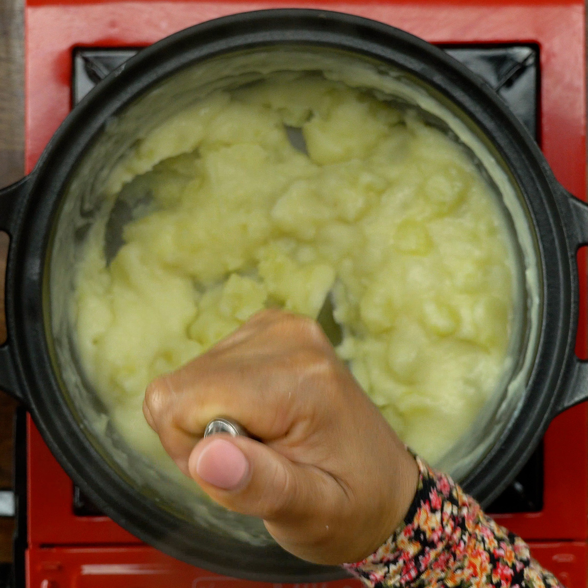 Amassando as batatas cozidas com leite.