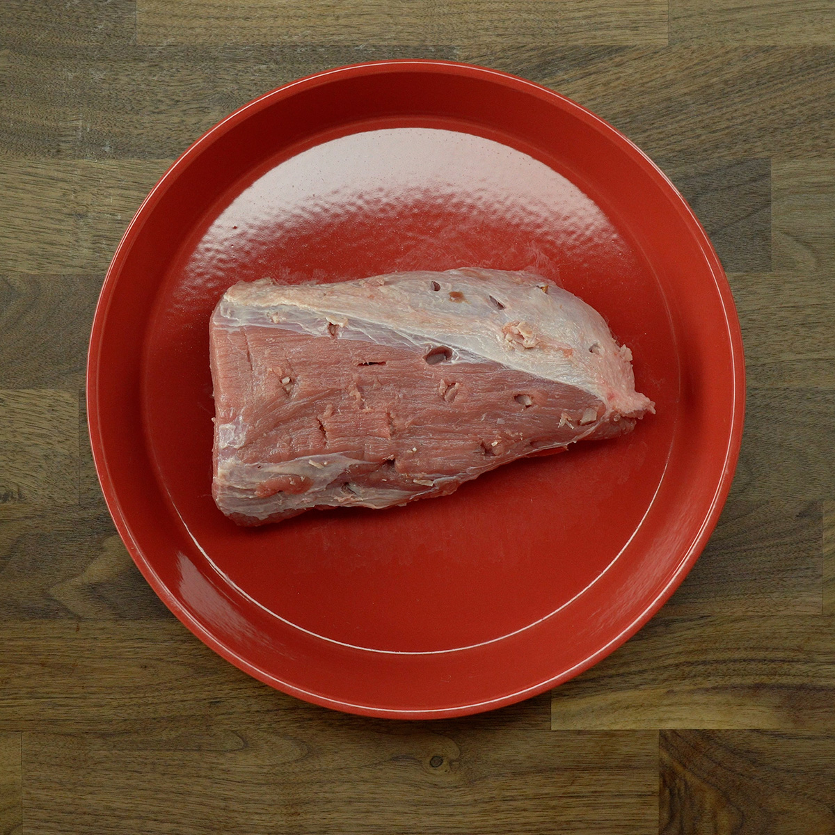 Lagarto cru com furos recheados com bacon em cubos.