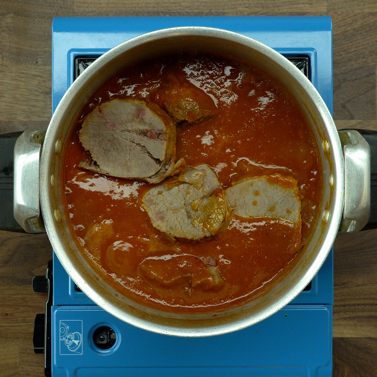 Lagarto fatiado sendo misturado ao molho encorpado na panela.