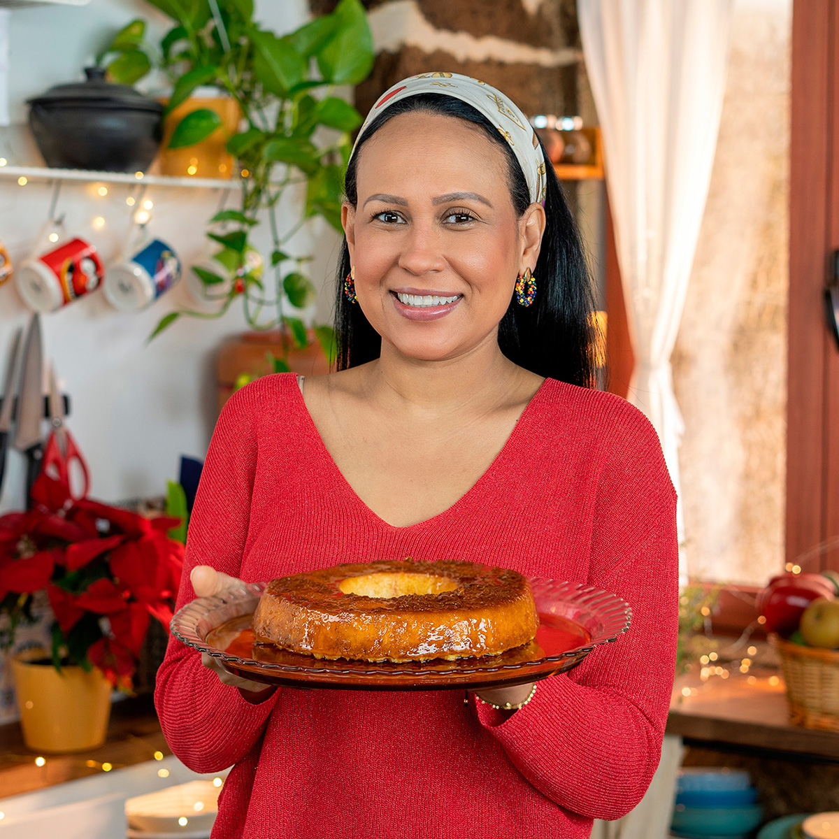 Mara Rodrigues segurando um prato de pudim de pão de forma com leite condensado.