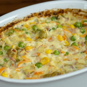 Travessa de arroz cremoso com bacon e presunto acabado de sair do forno.