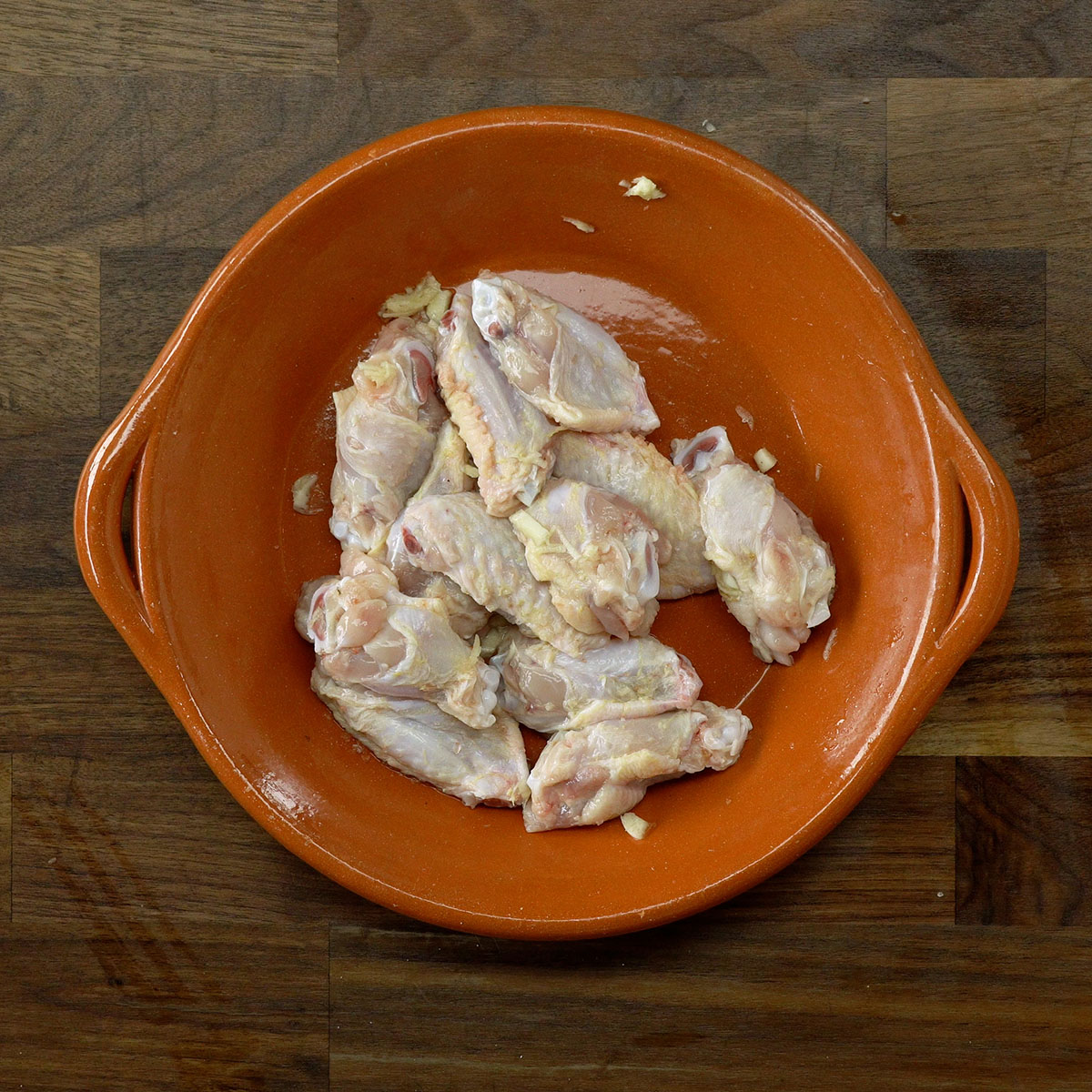 Asinhas de frango temperadas com alho e sal em uma tigela.