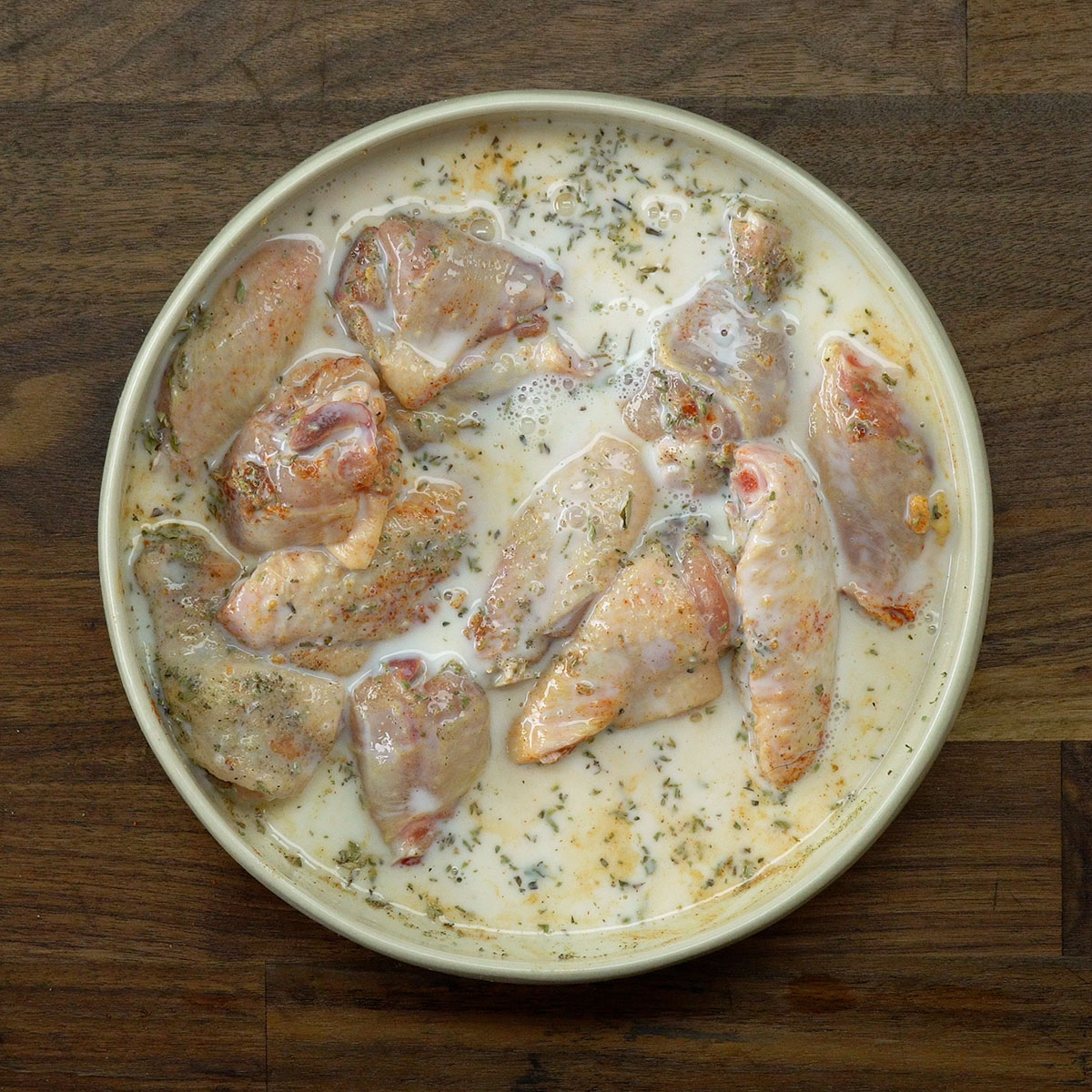 Adicionando leite às asas de frango para a marinada.