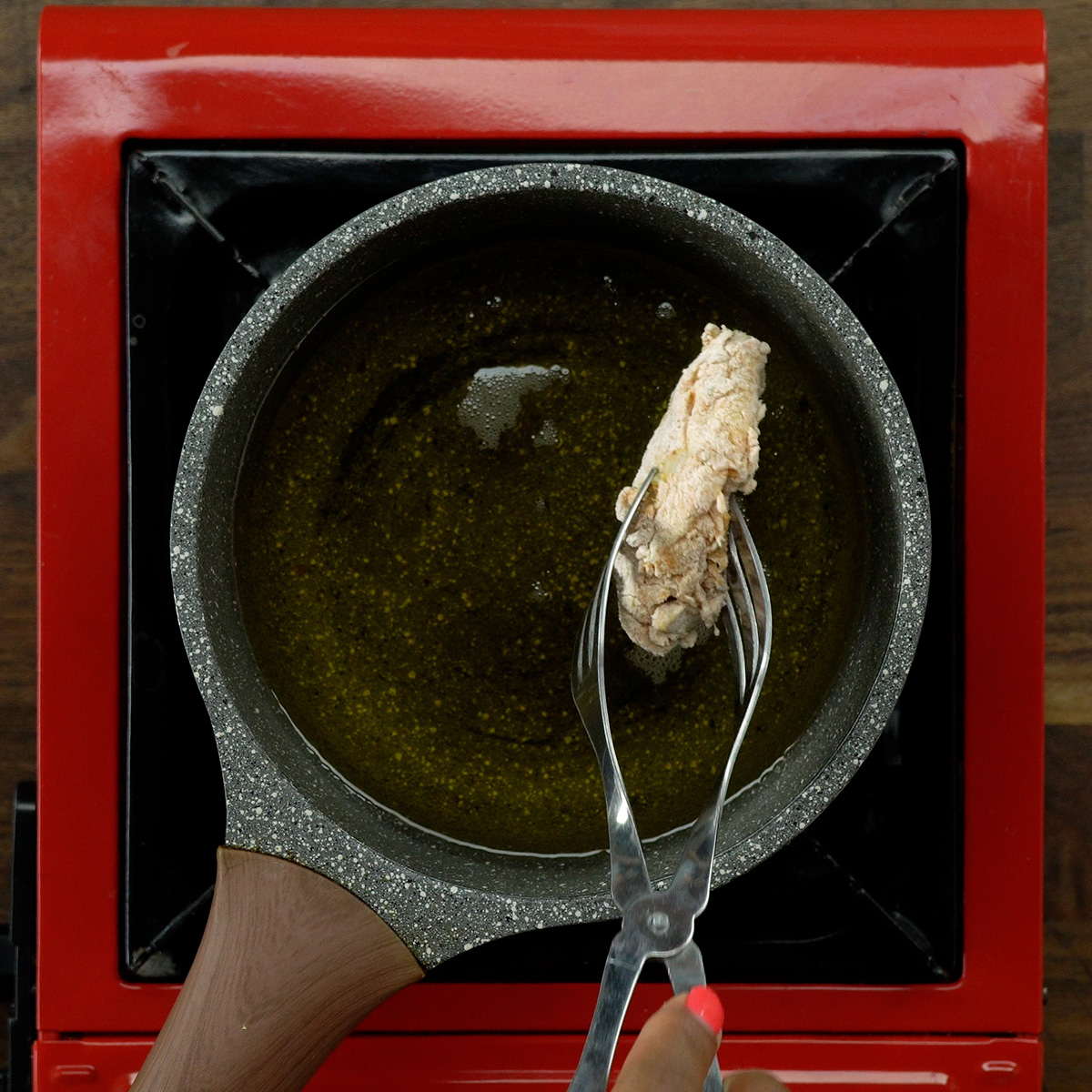 Asas de frango empanadas fritando no óleo quente.