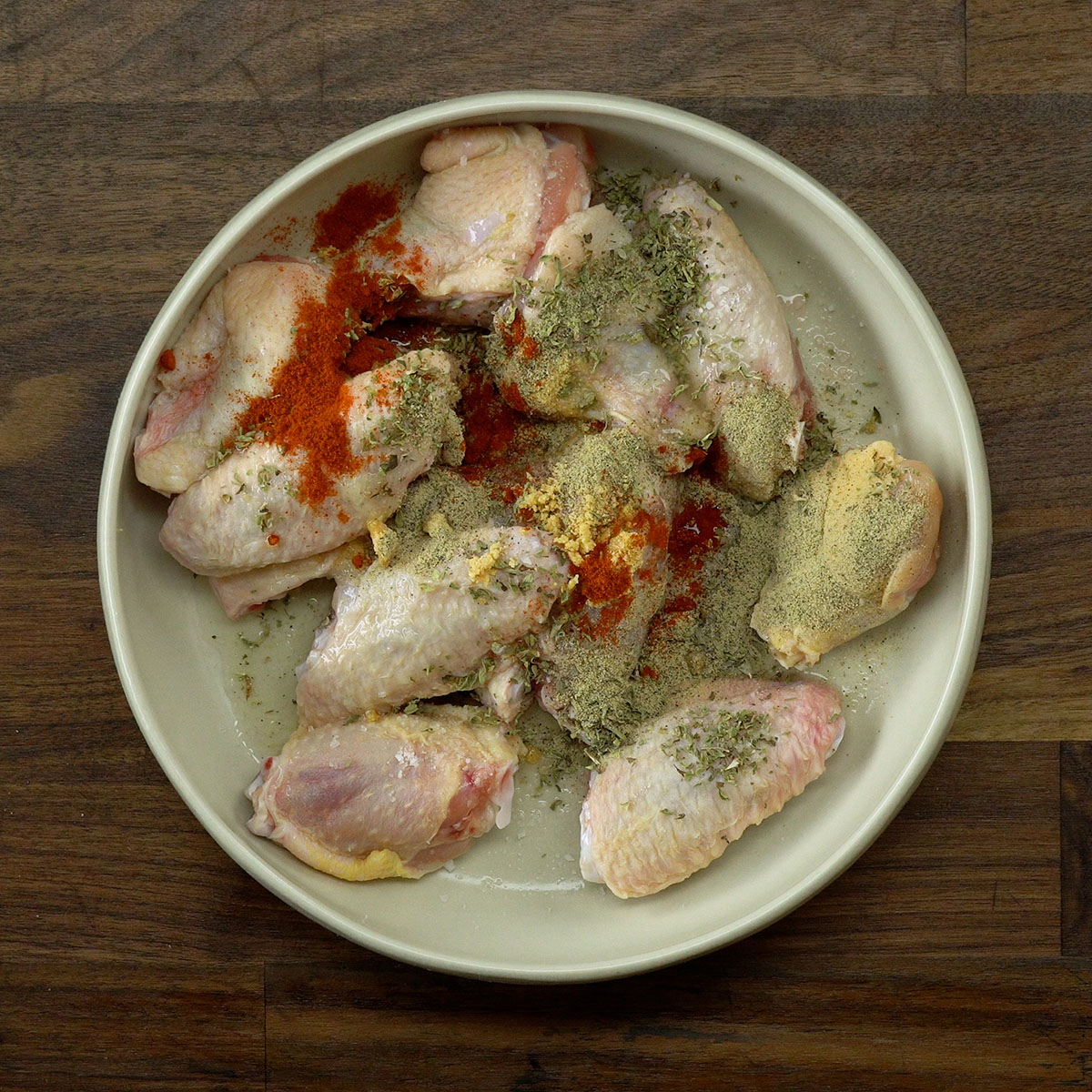 Asas de frango sendo temperadas e misturadas com limão e especiarias.