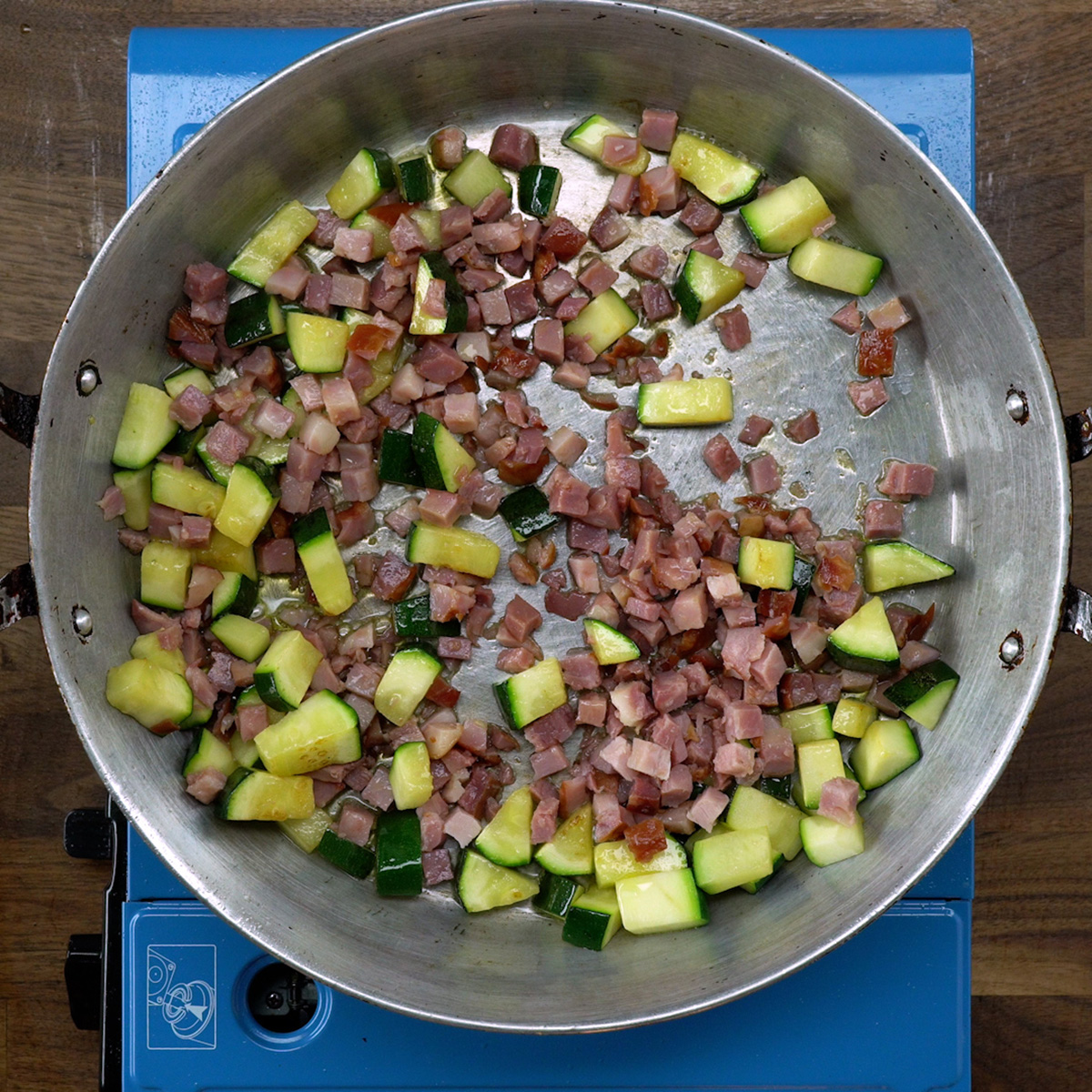 Bacon em cubos dourando na frigideira.