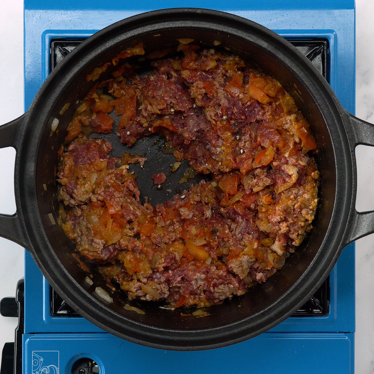 Carne moída sendo temperada com sal e pimenta.