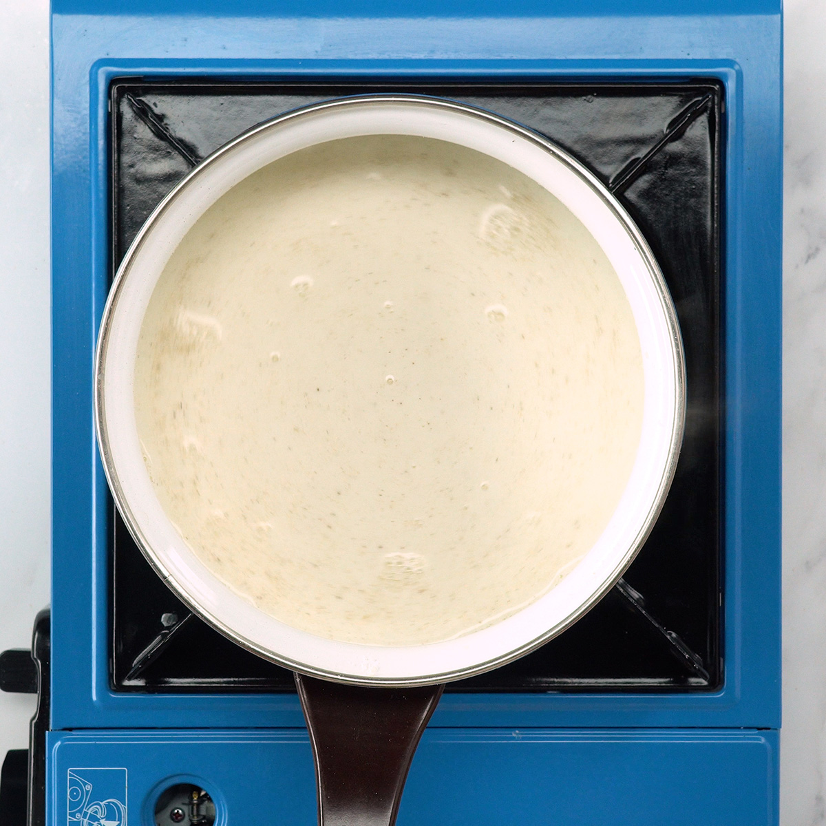Molho branco cremoso sendo preparado com leite e noz-moscada.
