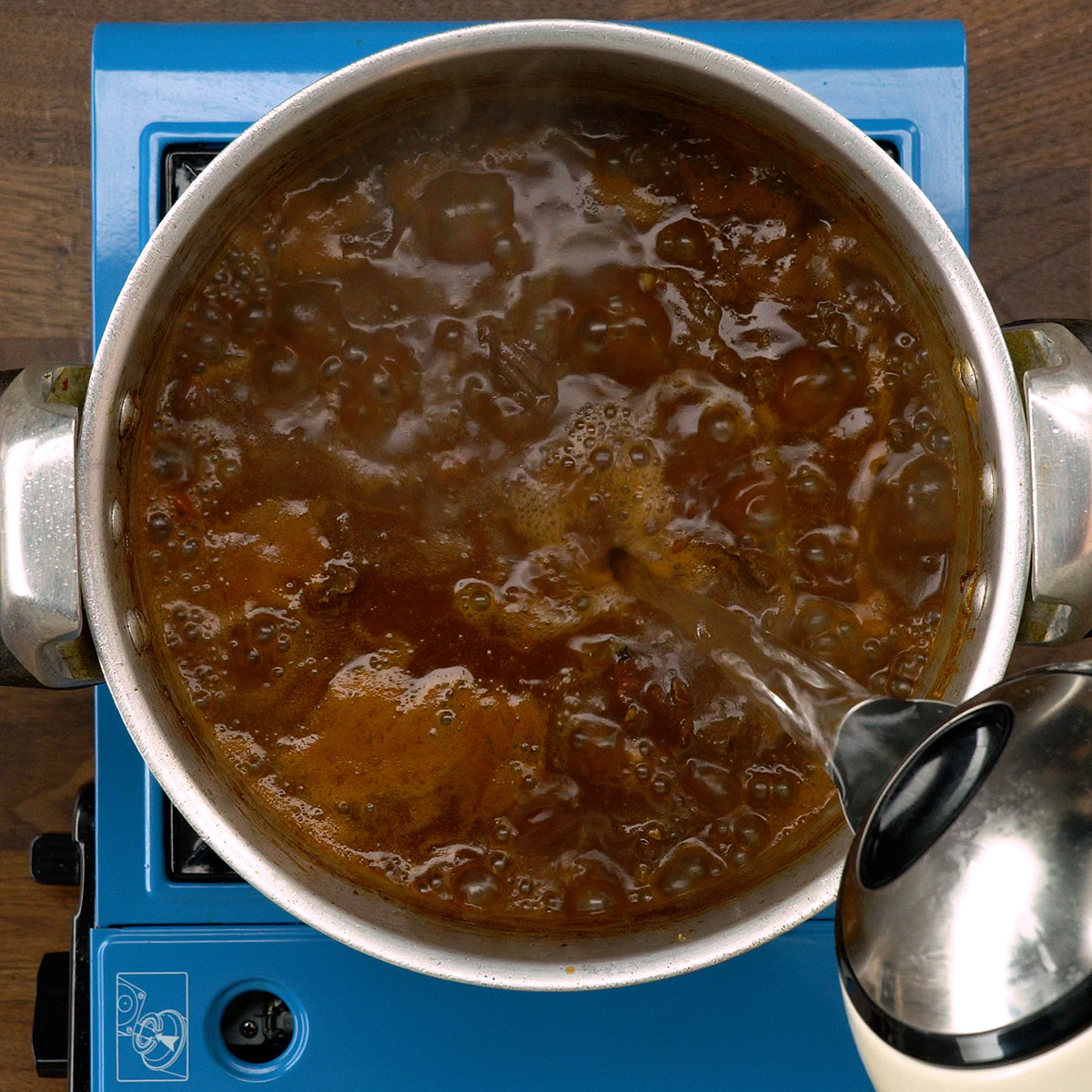 Água fervente sendo adicionada à carne na panela.