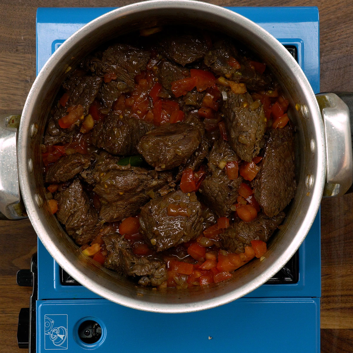 Carne refogando com cebola, alho, tomate e folha de louro.