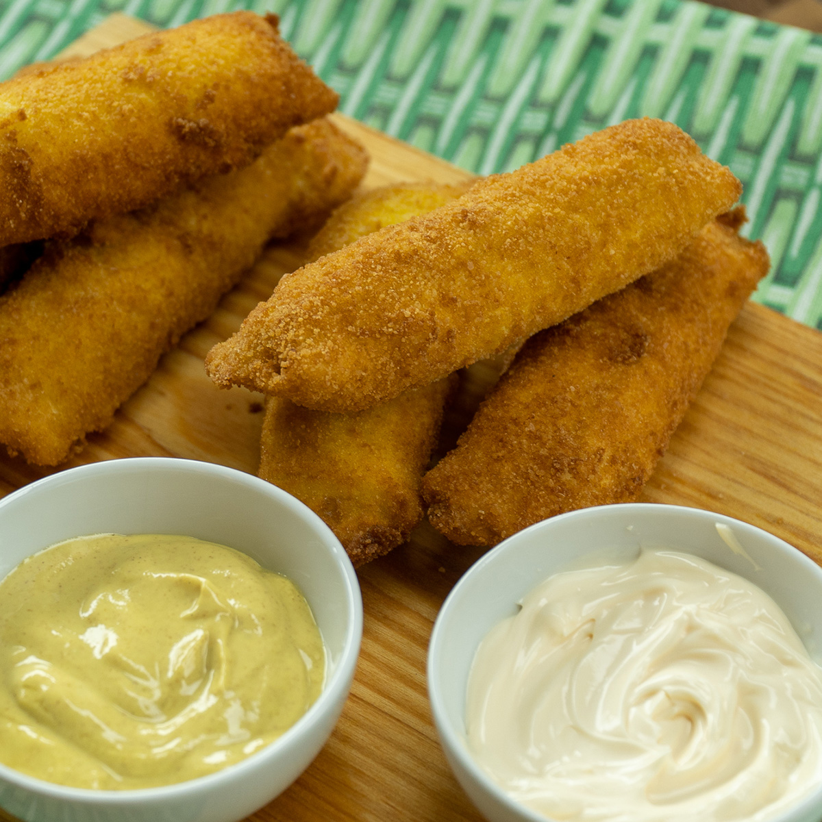 Enroladinho de pão de forma com presunto e queijo servido com molhos.