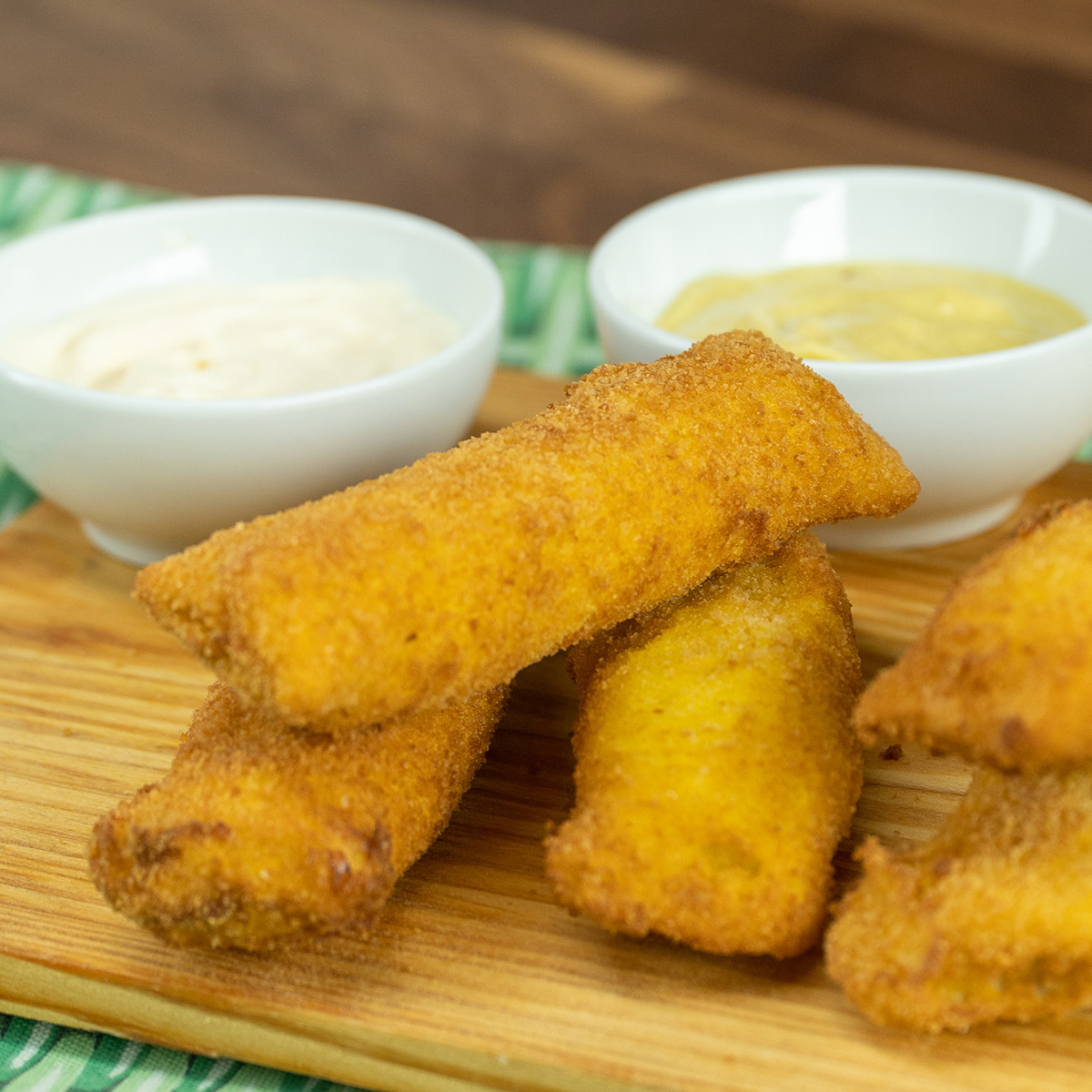 Enroladinho de pão de forma com presunto e queijo servido com molhos.
