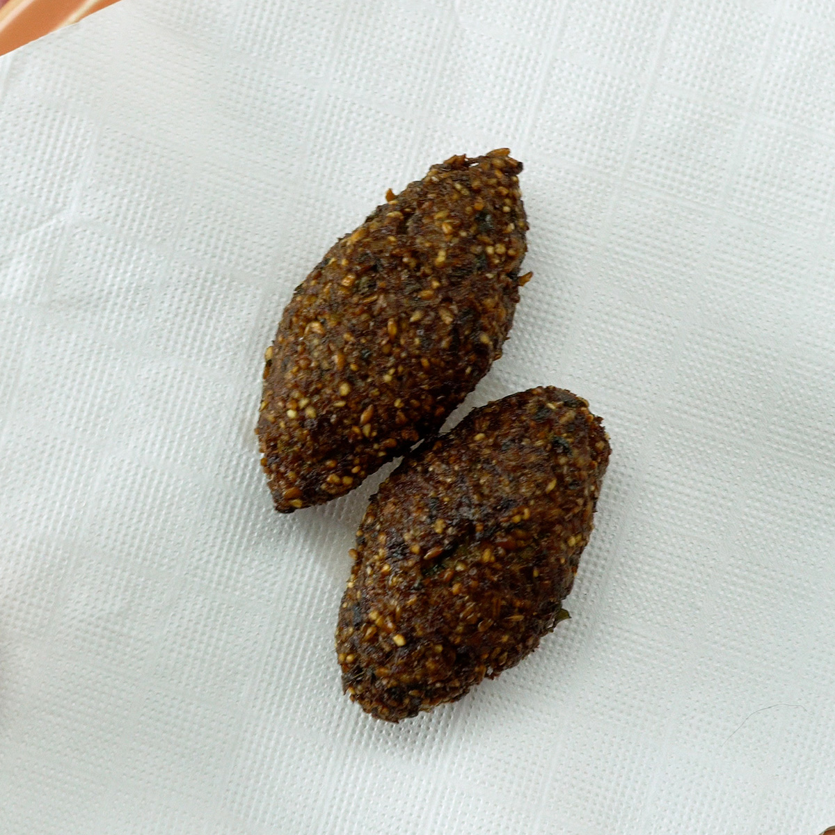 Kibes fritos escorrendo sobre papel toalha para remover excesso de óleo.