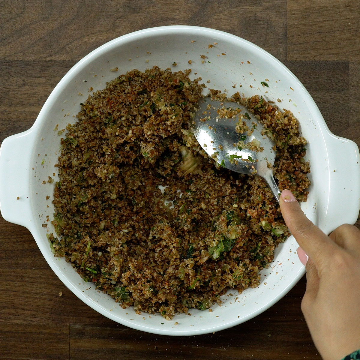 Trigo para kibe hidratado sendo temperado com sal, páprica e pimenta preta.