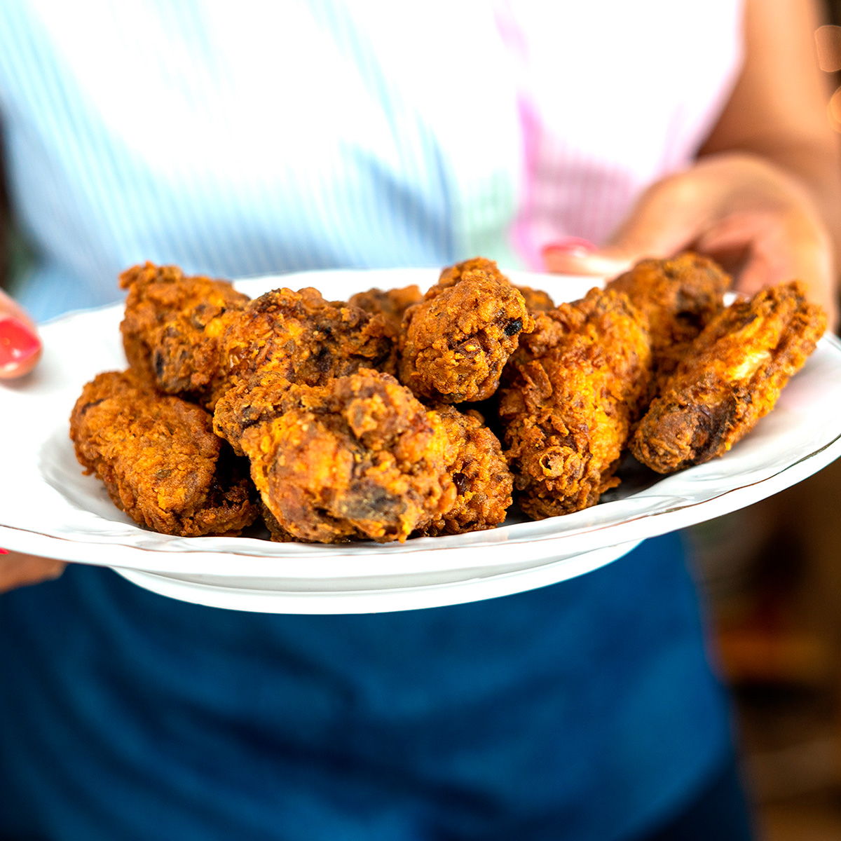 Mara Rodrigues segurando um prato com asas de frango crocantes.