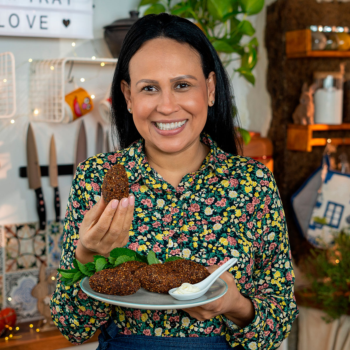 Mara Rodrigues segurando um prato com kibes recheados com queijo.