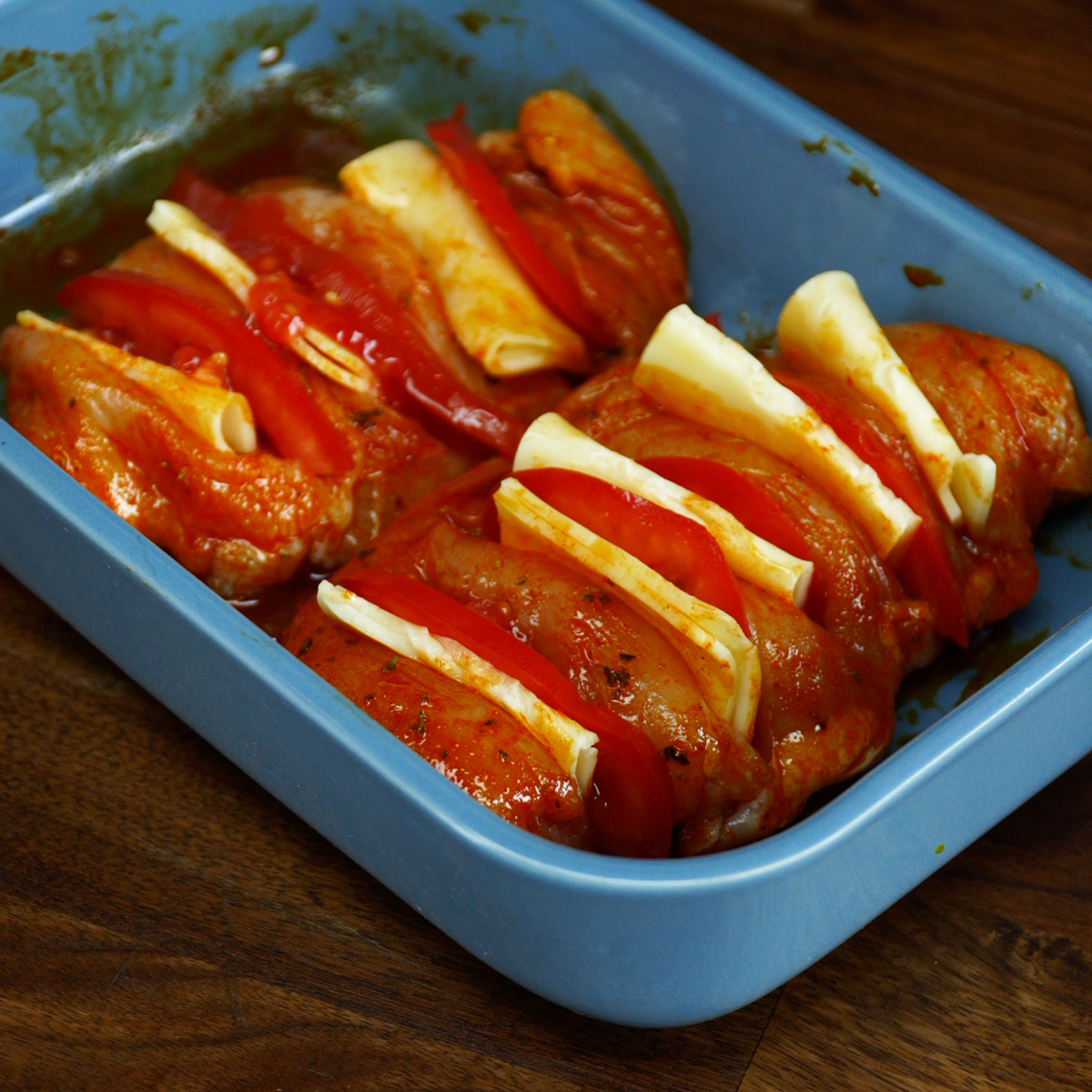 Peitos de frango recheados com tomate e muçarela sendo levados ao forno.