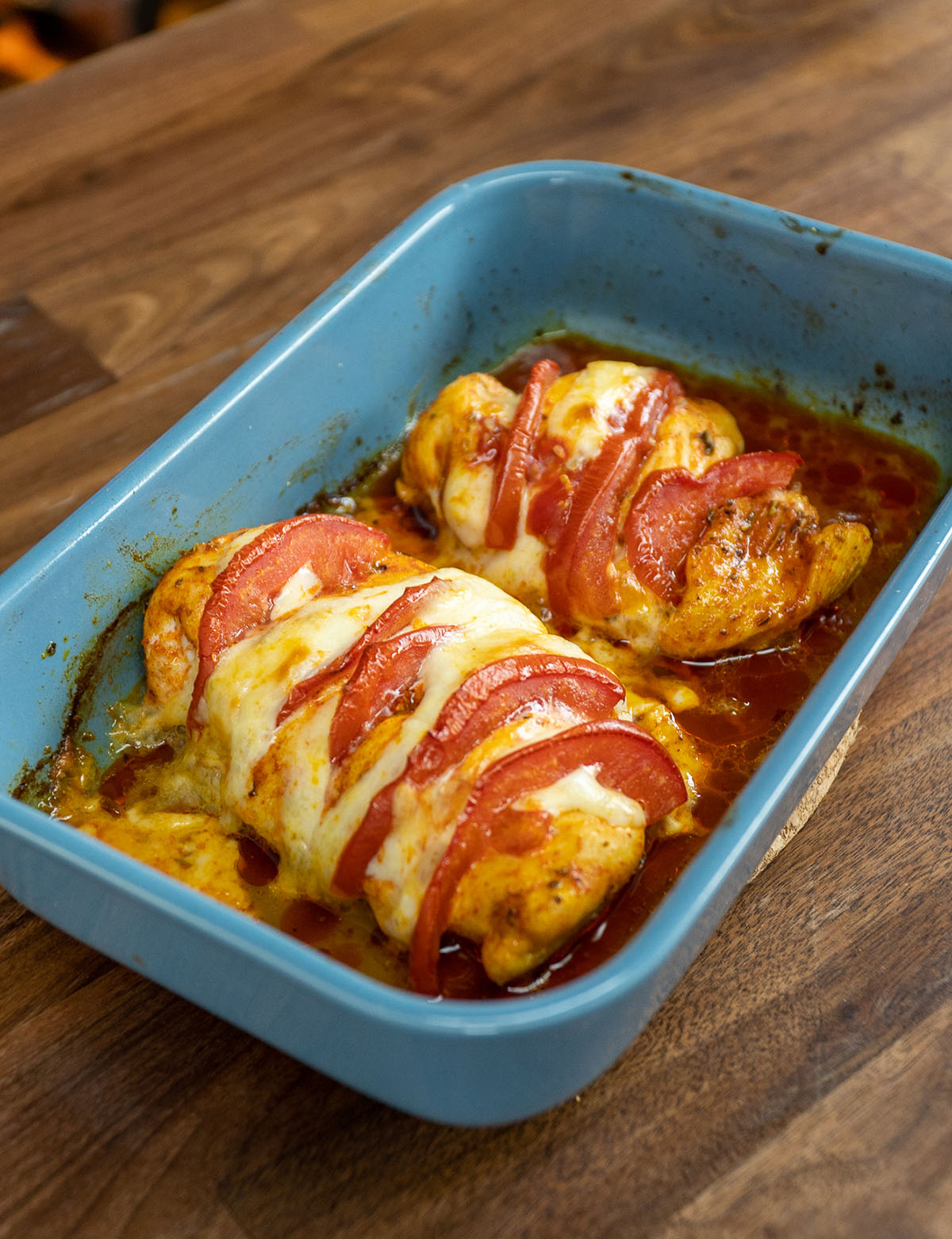 Peitos de frango recheados com tomate e muçarela saindo do forno.
