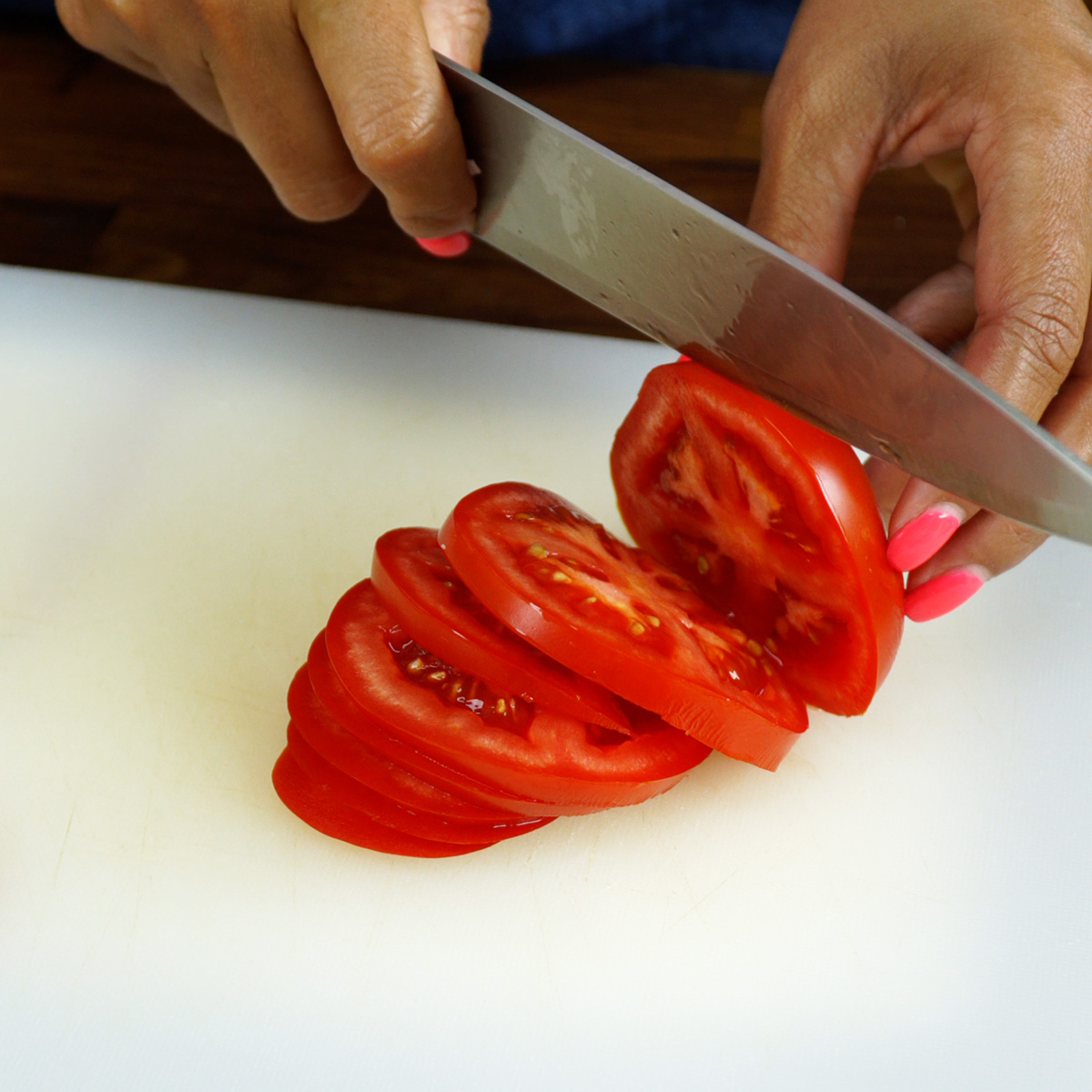 Tomate cortado em rodelas e em formato de meia-lua sobre uma tábua.