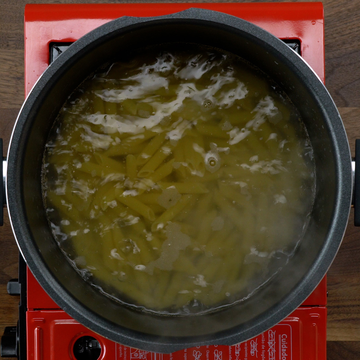 Penne cozinhando em água fervente com sal.