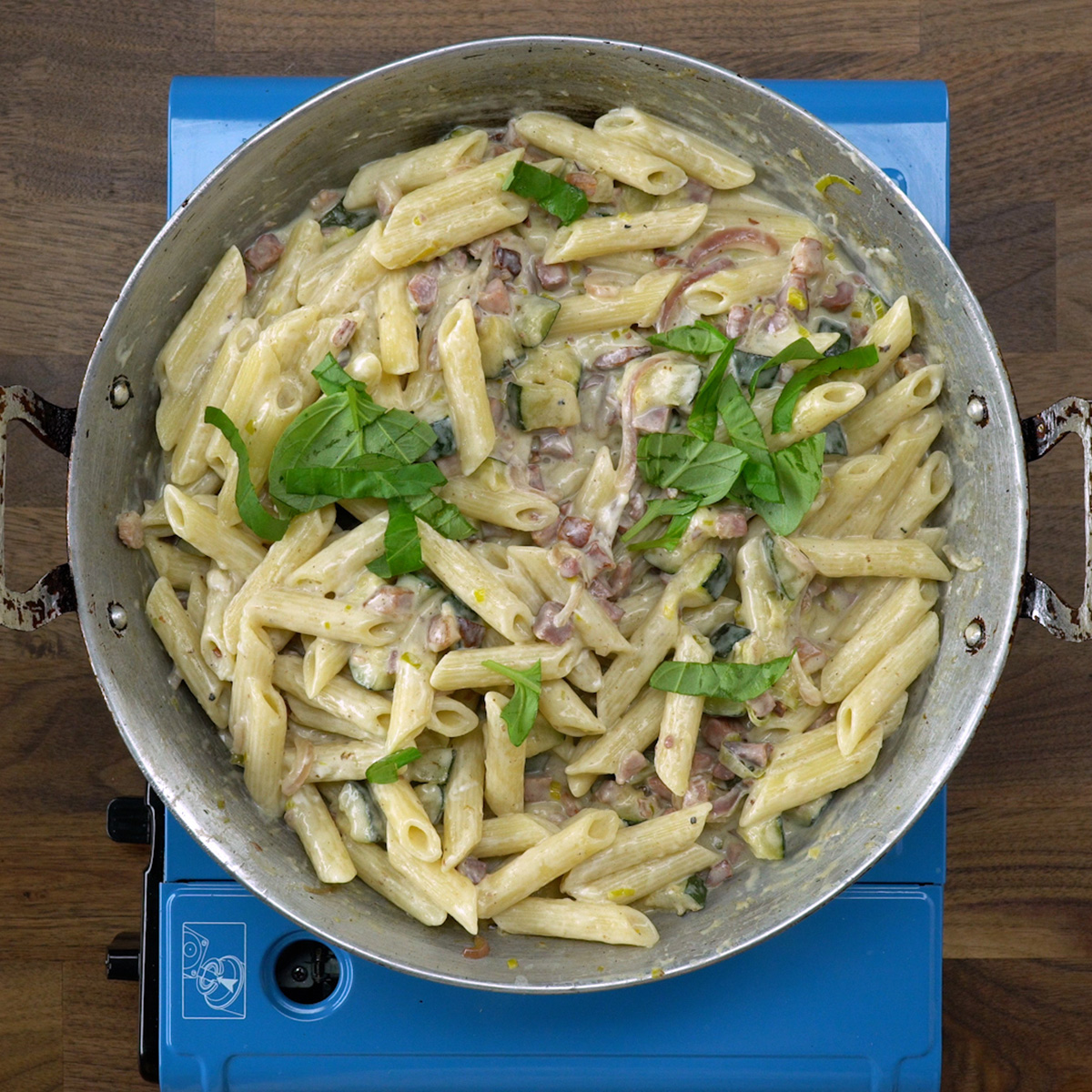 Penne misturado ao molho cremoso com bacon, abobrinha e manjericão.