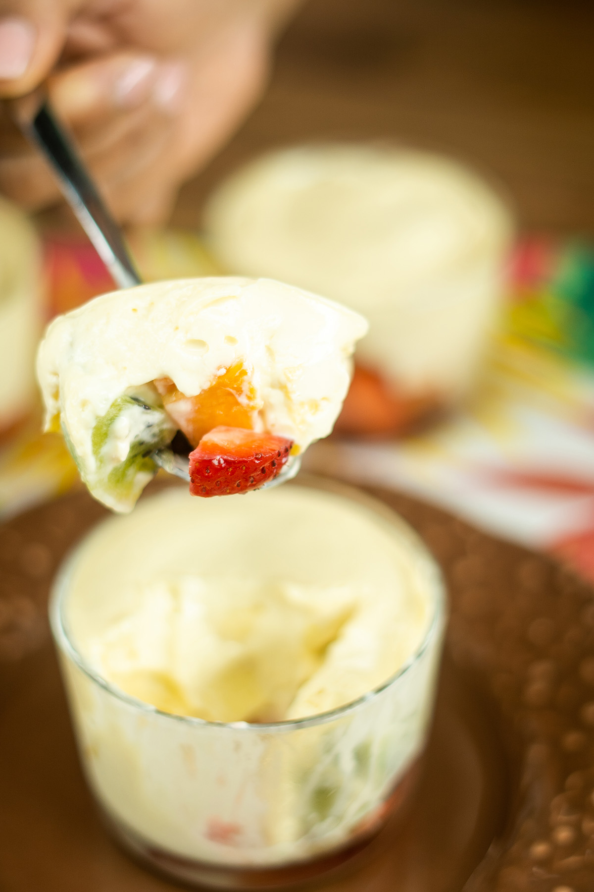 Colher servindo uma porção da sobremesa gelada de frutas com mousse de maracujá.