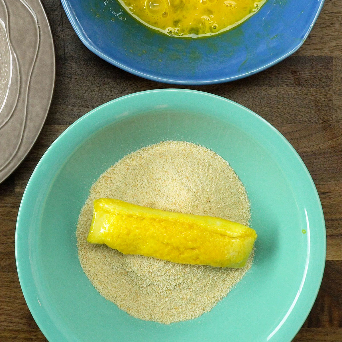 Enroladinho coberto com farinha de rosca antes da fritura.