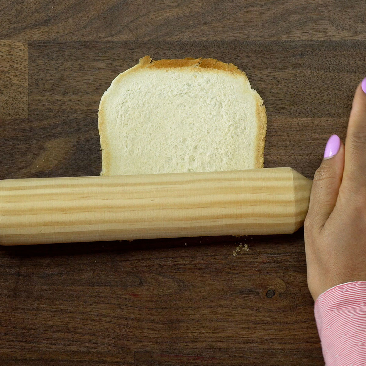 Rolo de massa achatando fatias de pão de forma.