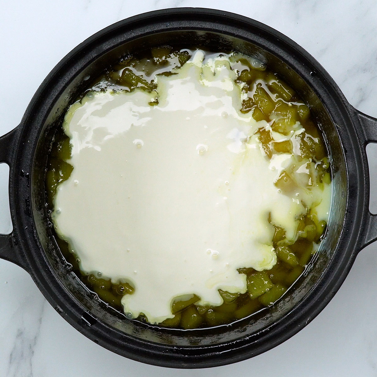 Adicionando o leite condensado e o creme de leite na panela.