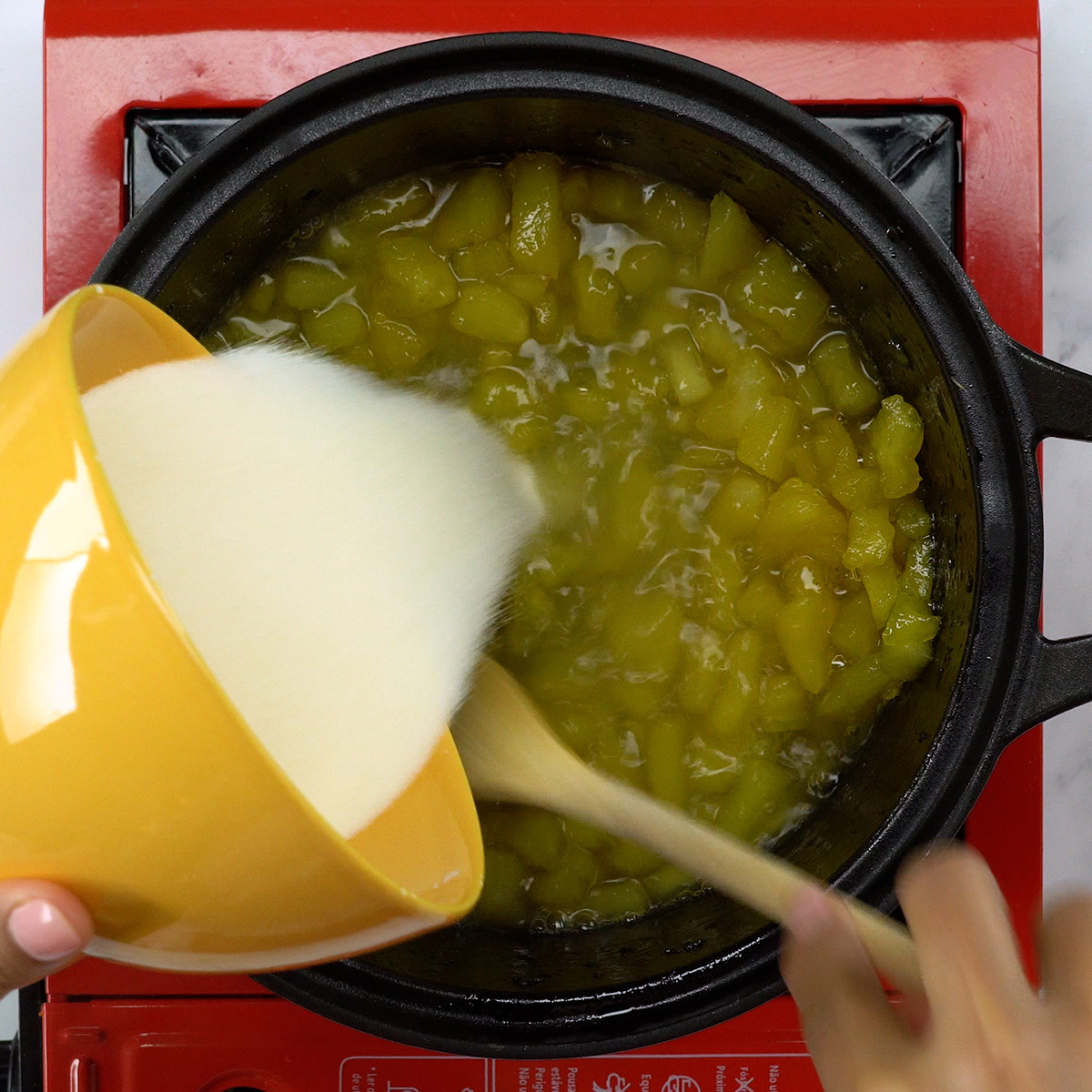 Gelatina sabor abacaxi sendo misturada ao abacaxi quente na panela.
