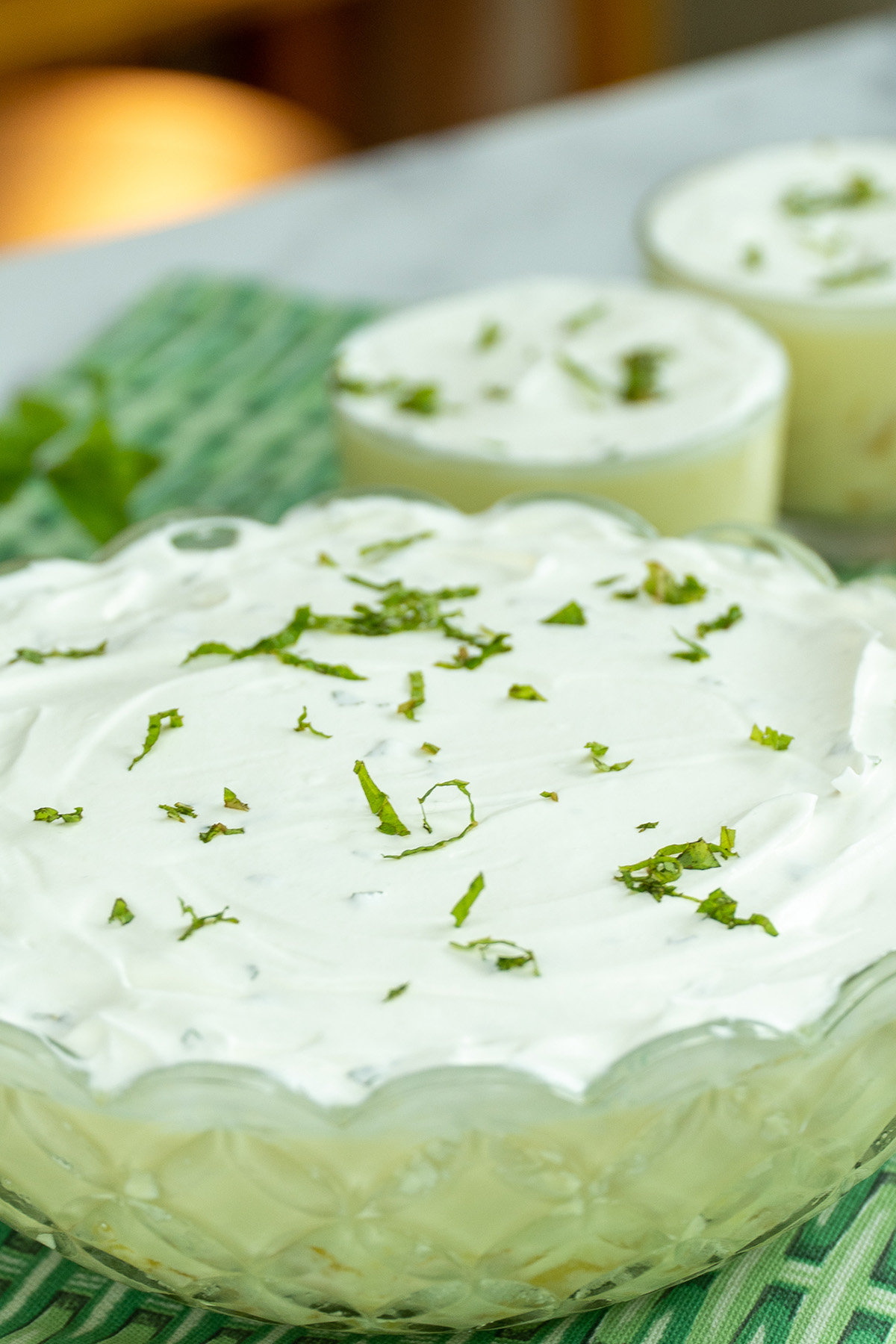 Sobremesa de abacaxi cremosa coberta com chantilly e decorada com hortelã picada.