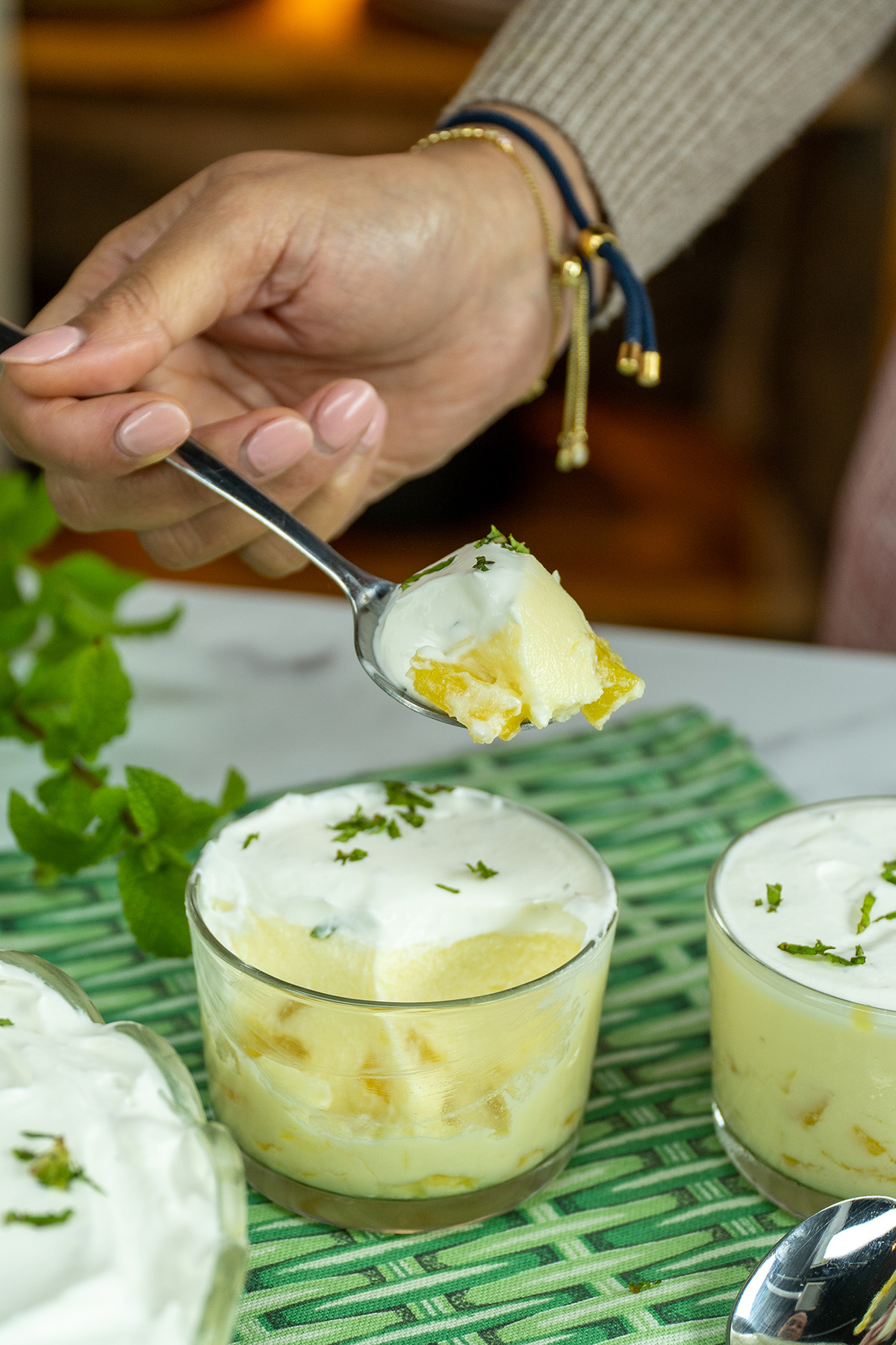 Sobremesa de abacaxi cremosa coberta com chantilly e decorada com hortelã picada, servida no copo.