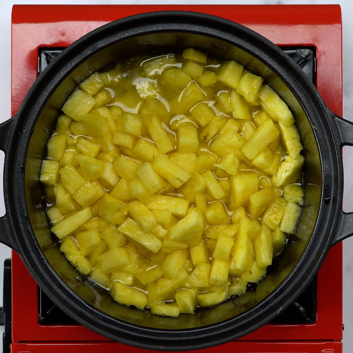 Abacaxi em cubos cozinhando com açúcar e água.