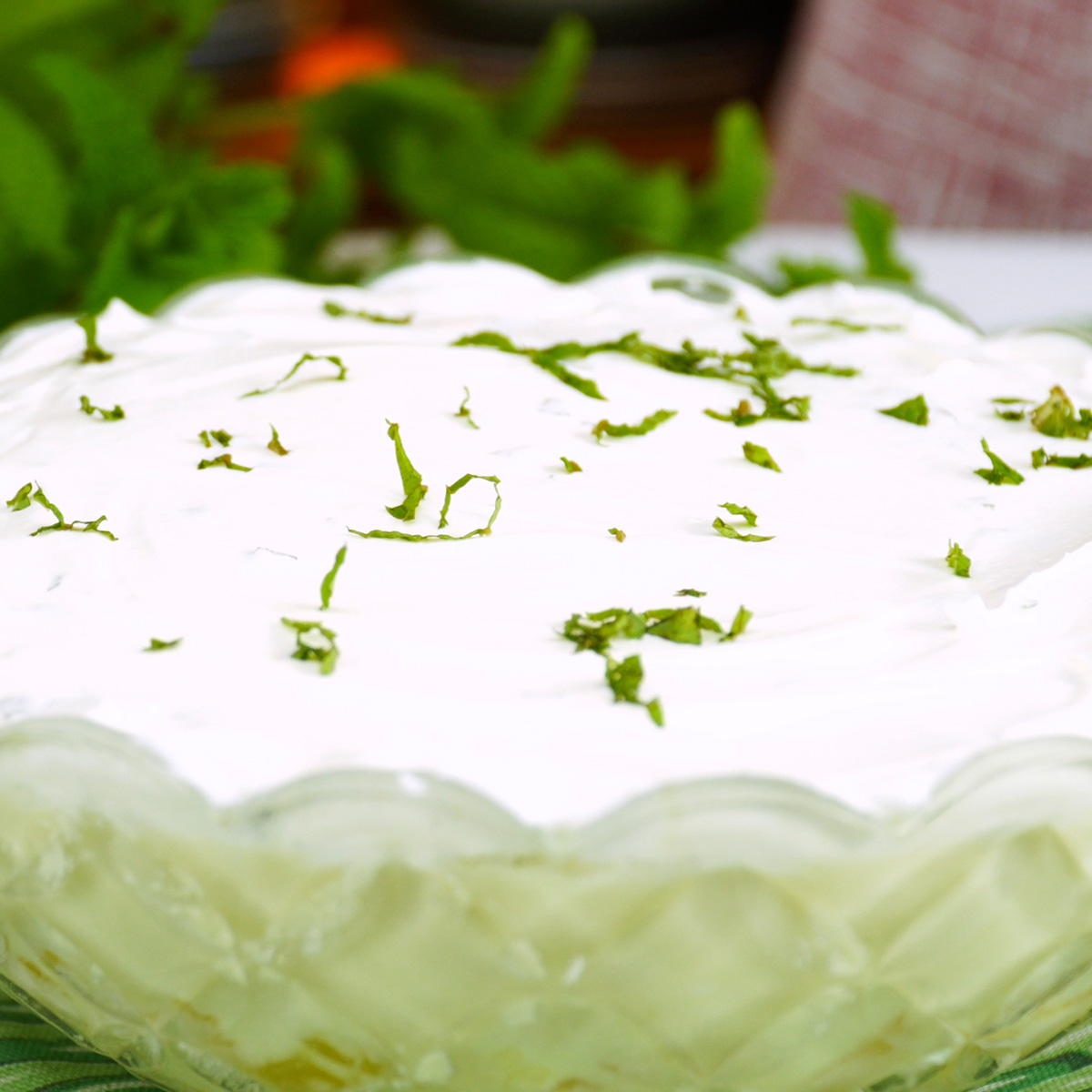 Sobremesa de abacaxi cremosa coberta com chantilly e decorada com hortelã picada.