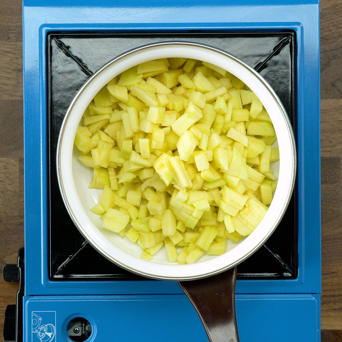 Maçãs picadas sendo aquecidas na panela para o recheio das tortinhas de maçã fritas.