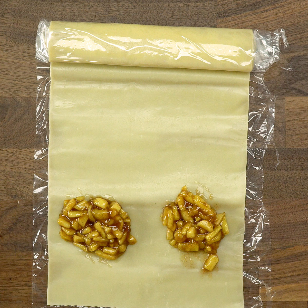 Massa de pastel sendo recheada com maçã para tortinhas de maçã fritas.