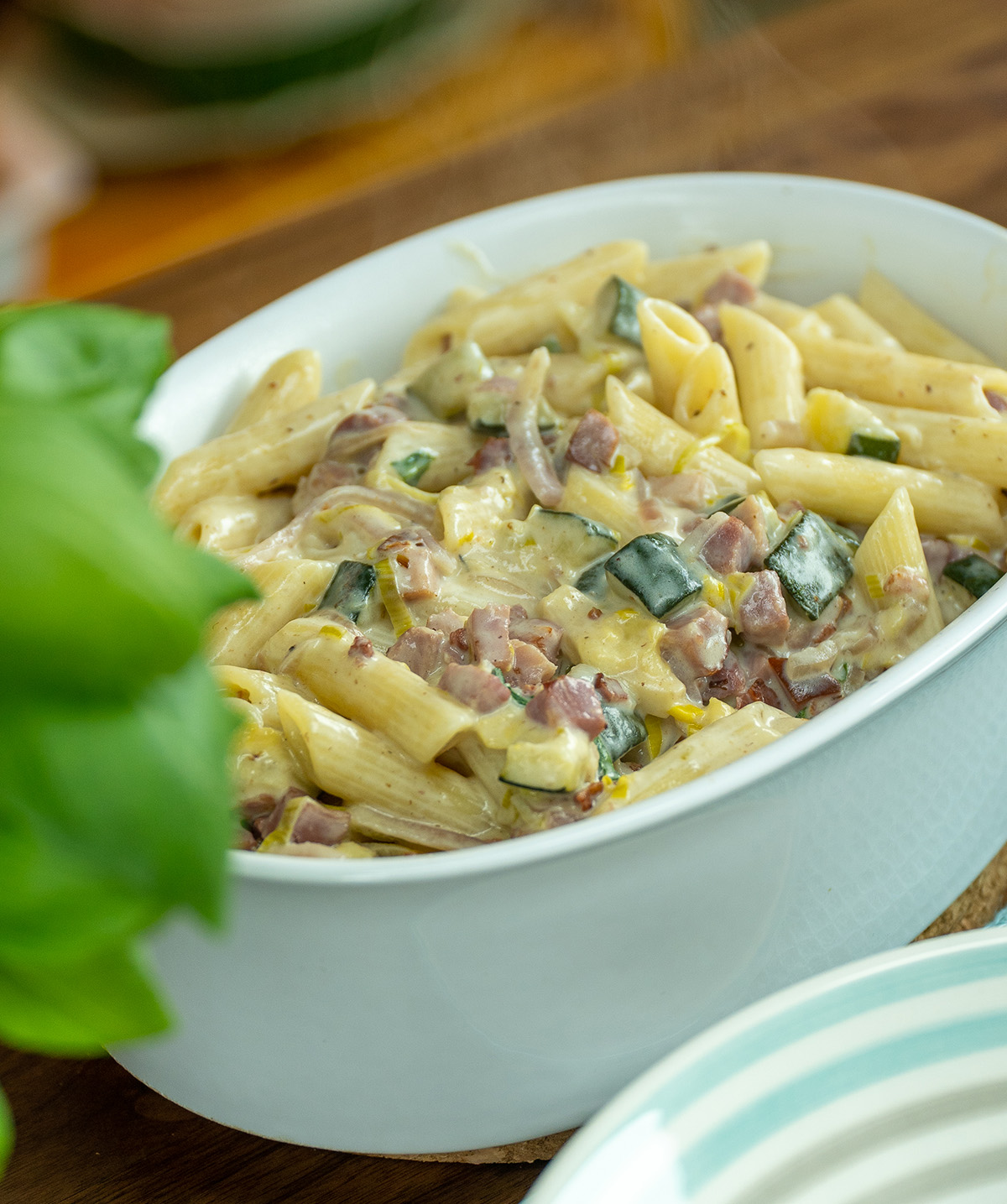 Travessa com penne cremoso de abobrinha e bacon.