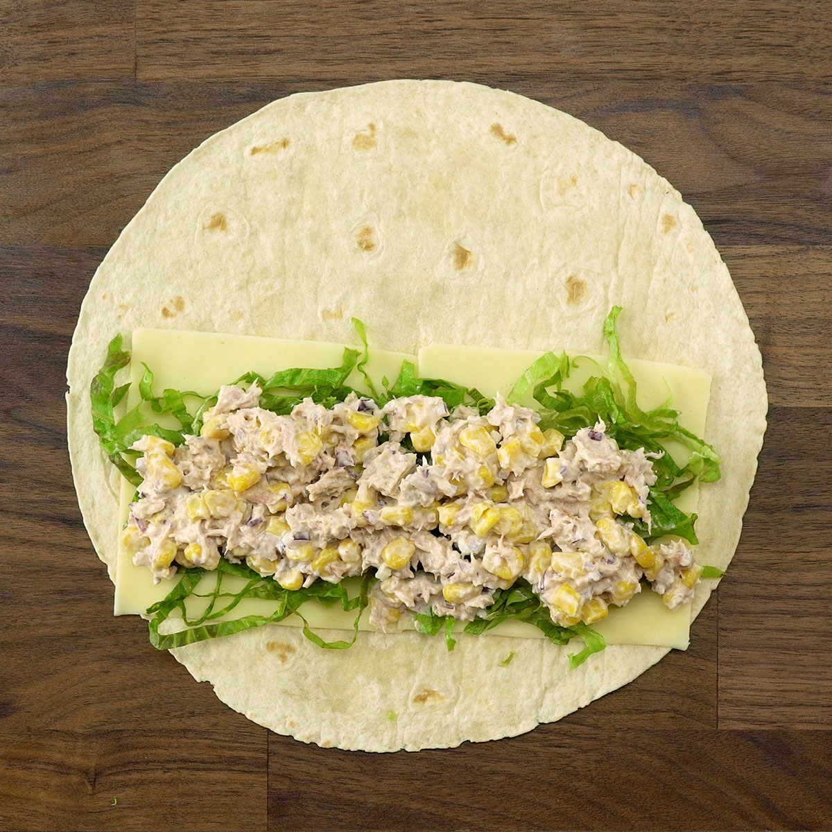 Recheio de atum sendo colocado sobre a alface no wrap.