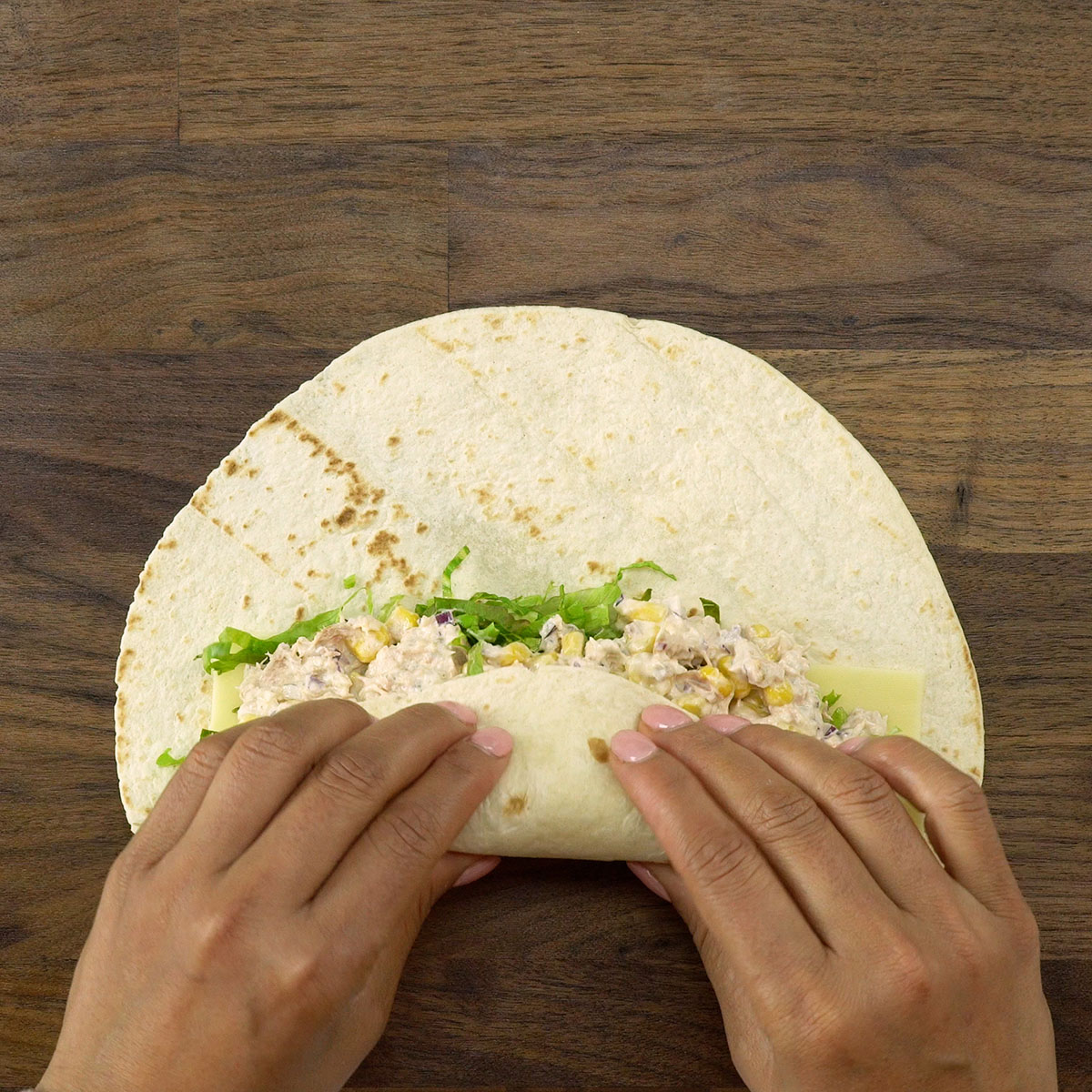 Wrap de atum sendo enrolado com cuidado para manter o recheio no centro.