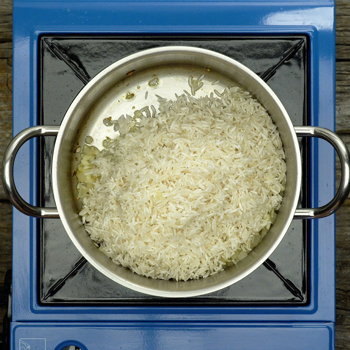 Arroz branco sendo misturado ao refogado na panela.