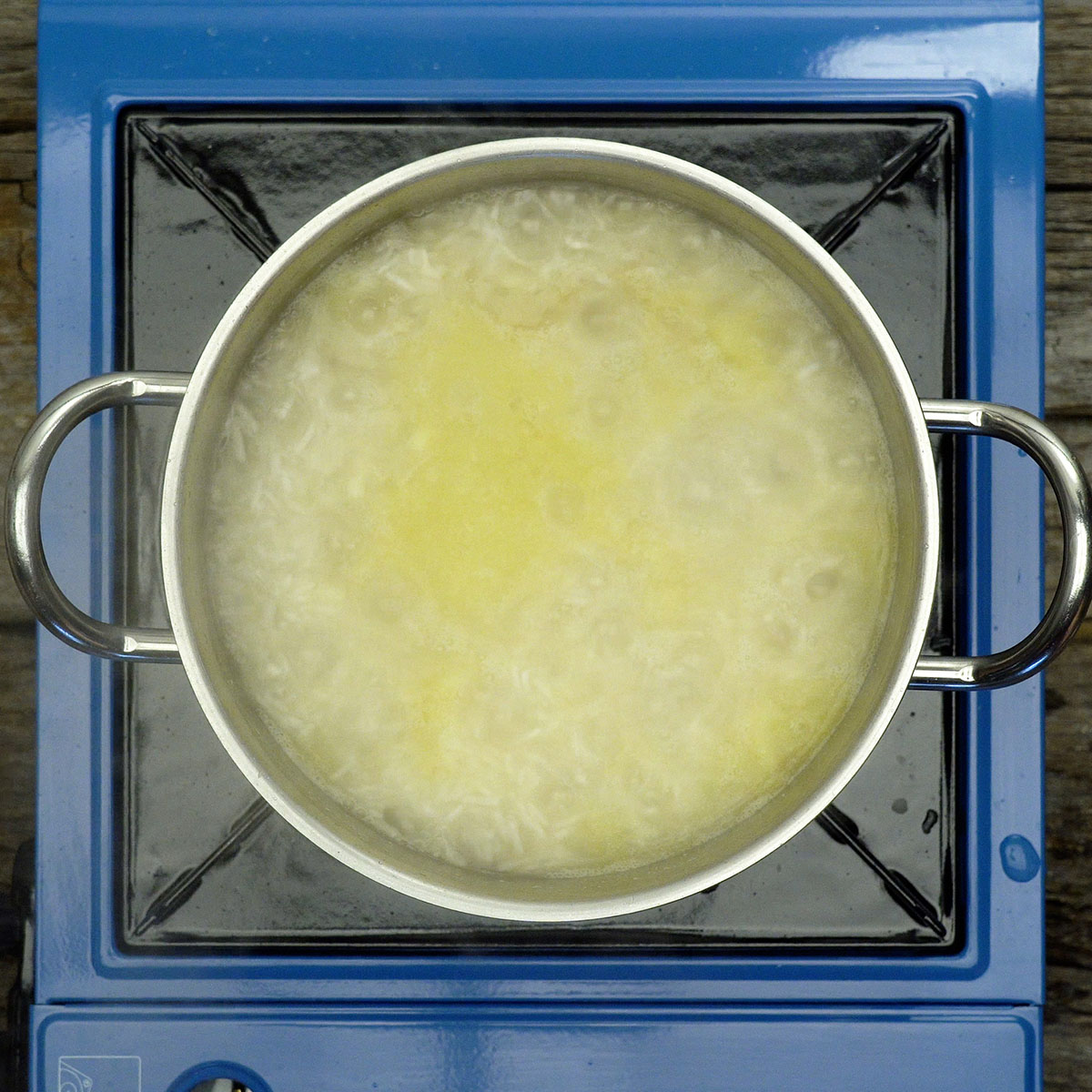 Arroz cozinhando na panela com água fervente e sal.