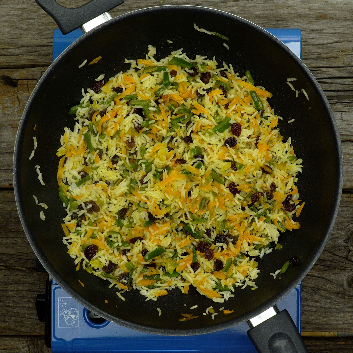 Arroz misturado com legumes coloridos em frigideira.