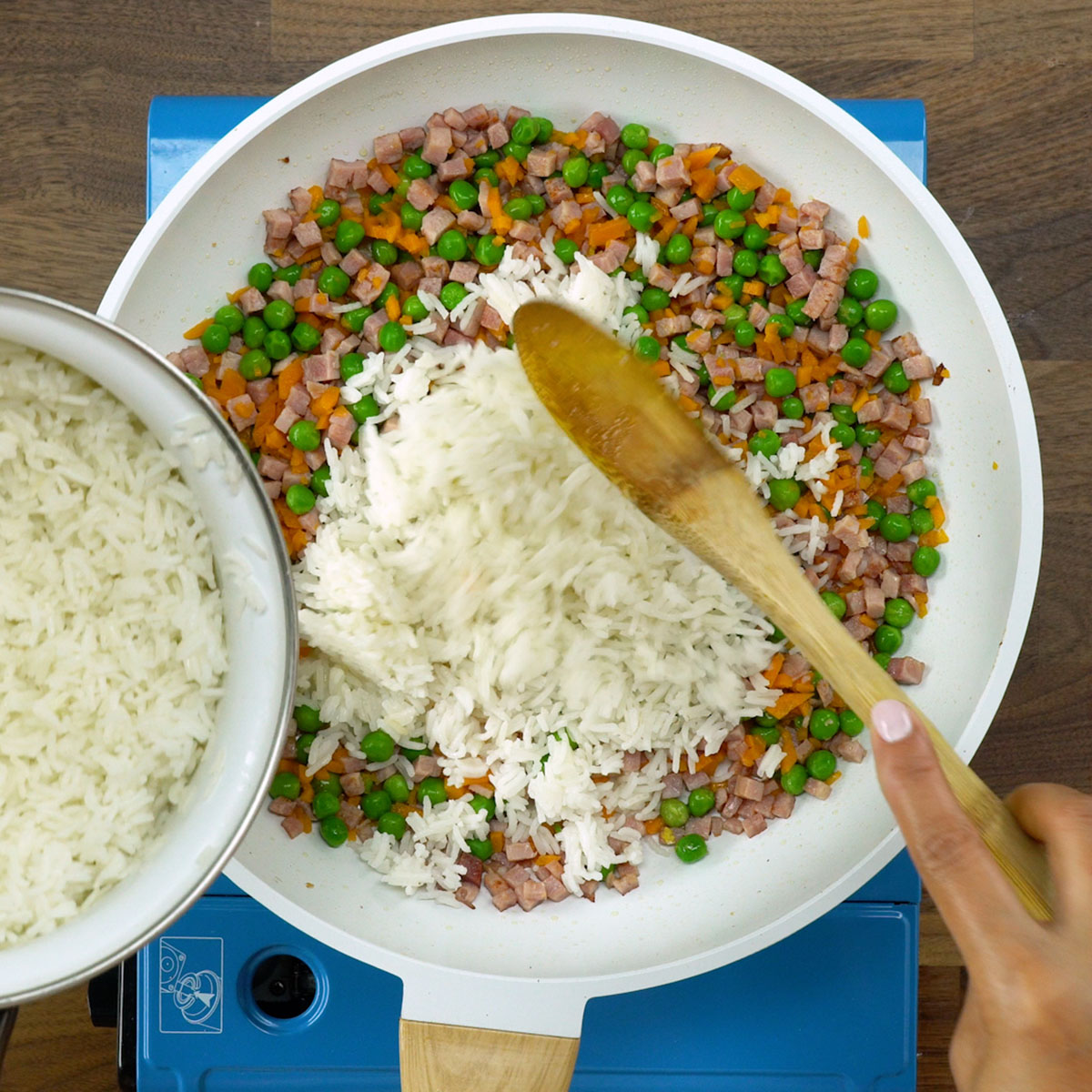 Arroz com cenoura e ervilhas sendo salteado na frigideira.